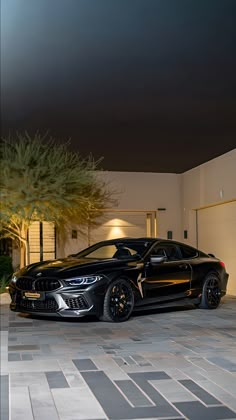 a black sports car parked in front of a house at night with its lights on