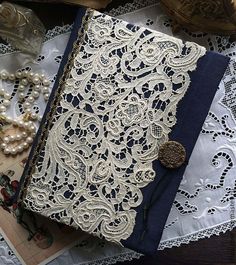 an open book with lace and pearls on it sitting on top of doily next to other items