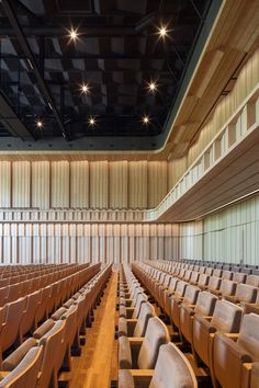 an empty auditorium with rows of seats facing the wall and ceiling lights on either side