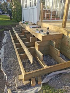 a wooden deck is being built on the side of a house with steps leading up to it