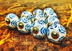 five blue and white ceramic balls with gold accents sitting on a table next to each other