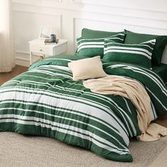 a green and white striped comforter set on a bed in a room with wood flooring