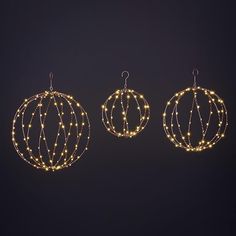 three christmas ornaments with lights hanging from them