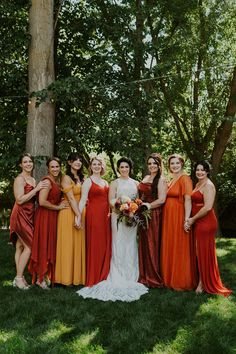 a group of women standing next to each other in front of a tree and grass field