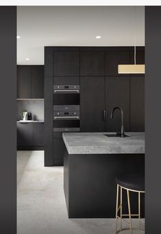 a modern kitchen with black cabinets and counter tops, along with a bar stool in the center