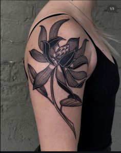 a woman's arm with a black and white flower tattoo on her left shoulder