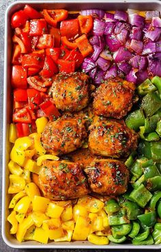 a tray filled with meat, peppers and onions next to other food items on a table