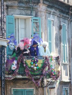 some people are standing on top of a balcony decorated with masks and garlands for mardi gras