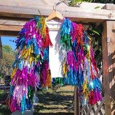 a colorful jacket is hanging on a wooden fence in front of a white t - shirt