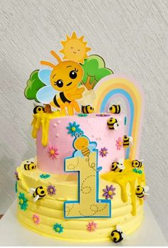 a yellow and pink birthday cake with bees on the top is decorated like a number one