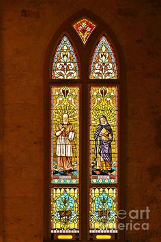 a stained glass window with two people standing next to each other in front of it