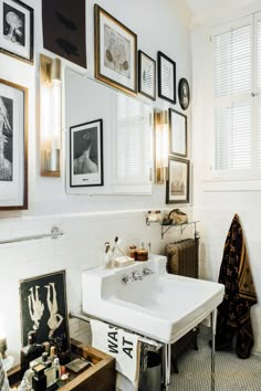 a bathroom with pictures on the wall and a white sink in front of a mirror