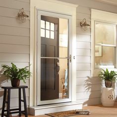 a house with white siding and two potted plants on the front door sill