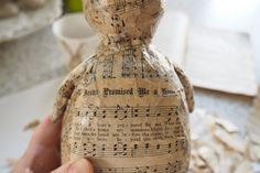 someone is holding an old paper doll with musical notes on it's back and hands