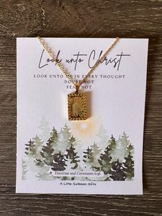 a gold necklace with an image of trees on it and the words look unto in every thought