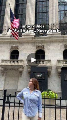 a woman standing in front of a building with an american flag on the side of it