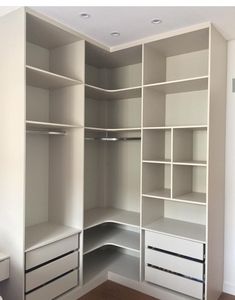 an empty walk in closet with white shelves and drawers