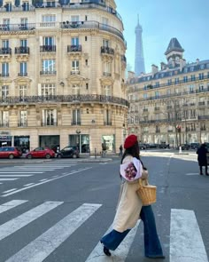 a woman walking across a street in front of tall buildings