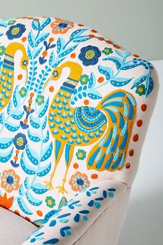 an upholstered chair with colorful designs on the armrests and back rest