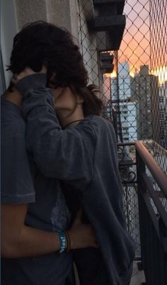 two people standing next to each other near a fence