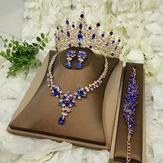 a tiara and necklace are on display in a box next to some white flowers