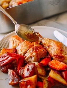 a plate with chicken, potatoes and carrots on it next to a serving spoon