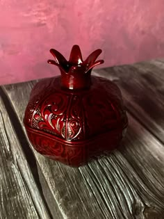 a small red vase sitting on top of a wooden table next to a pink wall