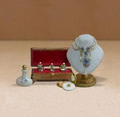 an assortment of jewelry sitting on top of a table next to a vase and bottle