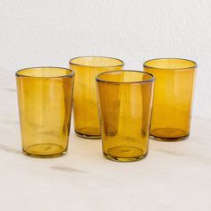 four yellow glass cups sitting on top of a table