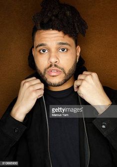 a man with dreadlocks on his hair is posing in front of a brown background