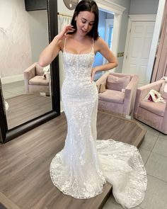 a woman standing in front of a mirror wearing a wedding dress