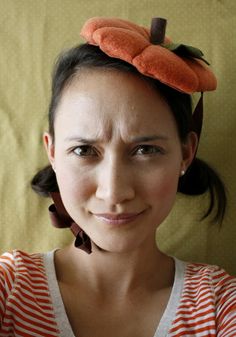 a woman with a hat on top of her head smiling at the camera while wearing an orange and white striped shirt