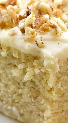 a piece of cake with white frosting and nuts on top