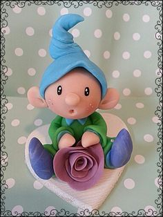 a small figurine is sitting on top of a cloth with a flower in it