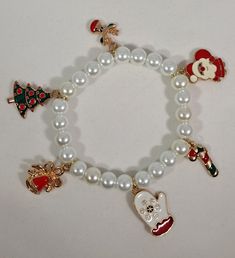 Bracelet: Christmas Charm Medium White Bead. This sweet charm bracelet is perfect for Christmas! The bracelet is 6.25 inches long. Made with clear stretch elastic beading cord, so it will stretch. One size fits most. Beads were purchased new. Christmas Themed Bracelets, Adjustable Christmas Beaded Bracelets, Adjustable Christmas Charm Bracelet For Gifts, Affordable Christmas Charm Bracelet, Cheap Christmas Holiday Charm Bracelet, Beading Cord, Bracelet Christmas, Christmas Bracelet