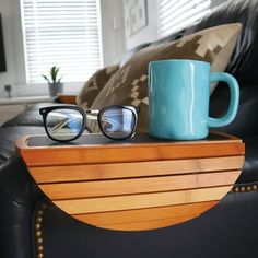 a pair of glasses sitting on top of a wooden table next to a blue mug