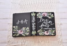 two personalized notebooks with floral designs on them sitting on a white tablecloth