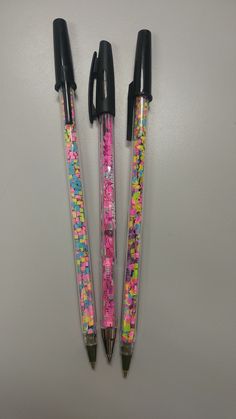 two pens with different designs on them sitting next to each other, one is pink and the other is black