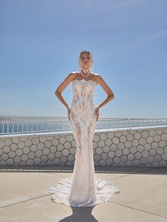 a woman in a wedding dress standing on the sidewalk with her hands on her hips