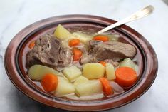 a bowl filled with meat, potatoes and carrots