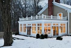 a white house with lots of windows in the front and side of it covered in snow