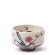 a white bowl with red flowers and branches painted on the side, sitting in front of a white background