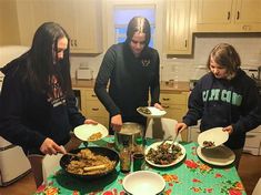 three girls standing around a table with plates of food