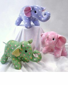 three stuffed elephants sitting on top of a white cloth covered bed with polka doted sheets