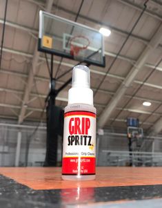 a bottle of grp spritz sitting on top of a wooden floor next to a basketball hoop