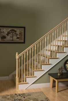 there is a white stair case next to a table with a vase on it and a framed tree in the background