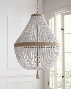 a chandelier hanging from the ceiling in a room with white walls and windows