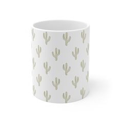 a white mug with green cactus print on it's side and the bottom half is empty