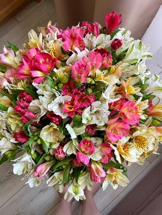 a woman holding a bouquet of pink and white flowers in her hands on the floor