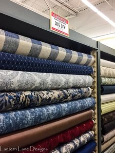 many different fabrics are on display in the store and one has a sale sign above it